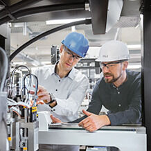 Two men in hard hats standing in front of a machine