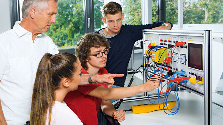Four people standing in front of a Pilz Education System (PES)
