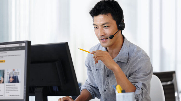 A person wearing a headset at a computer workstation during an online consultation on IO-Link Safety